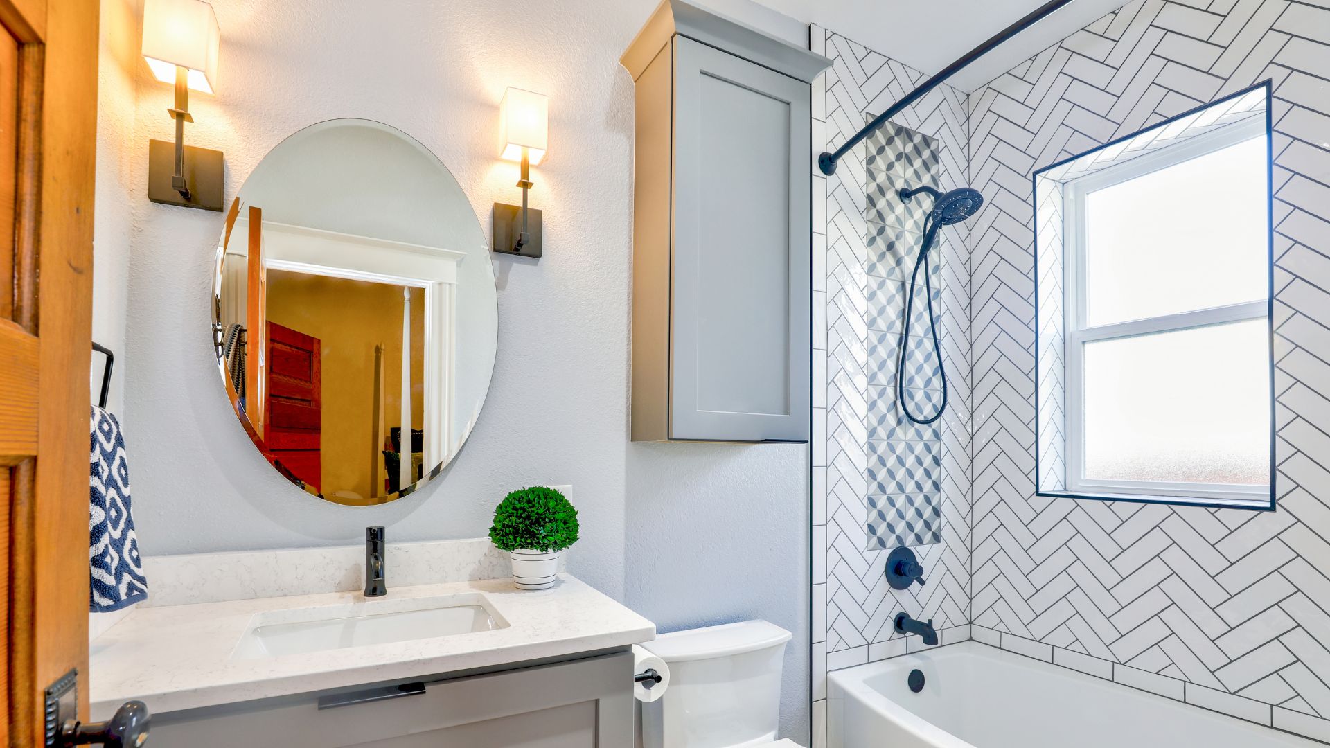 Modern bathroom with white tiles, round mirror, and blue-black fixtures