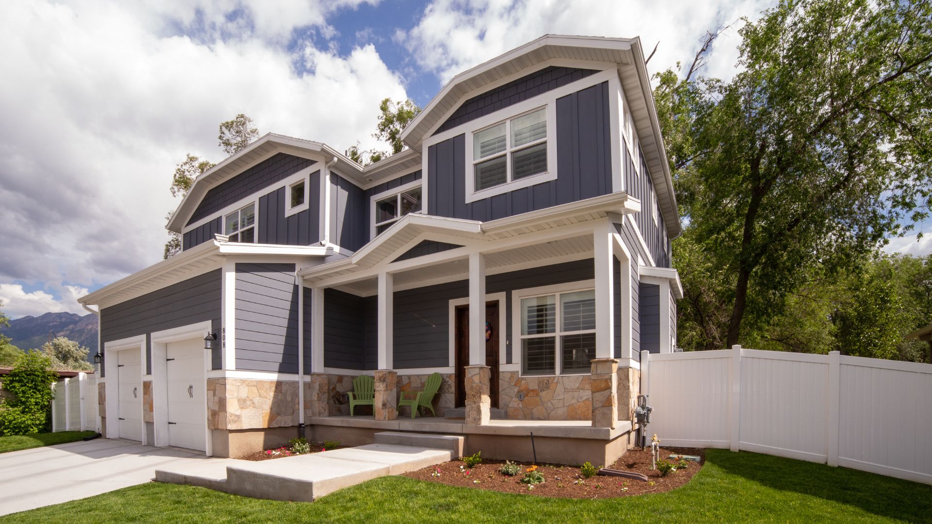Modern two-story house with stone base, gray siding, and front porch