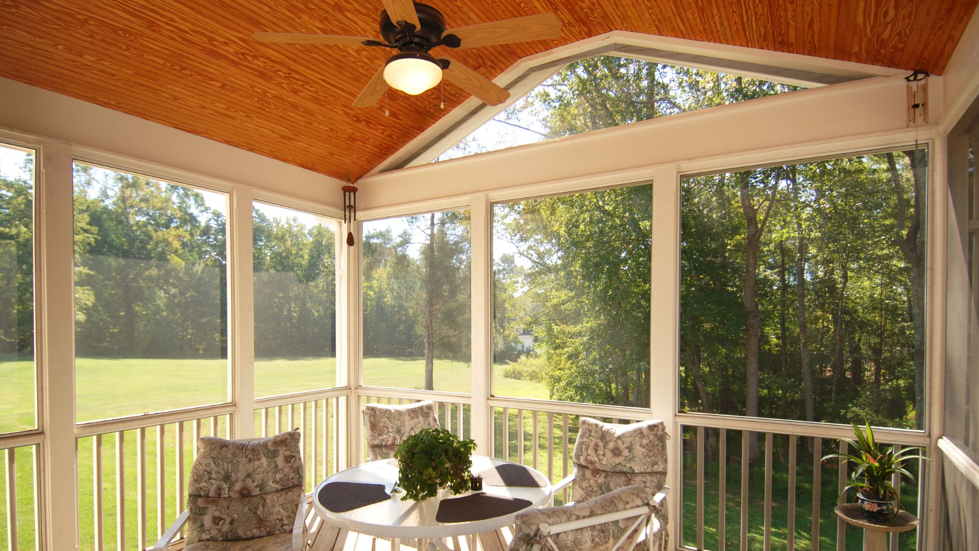 Cozy screened porch with wooden ceiling, furniture, and forest view